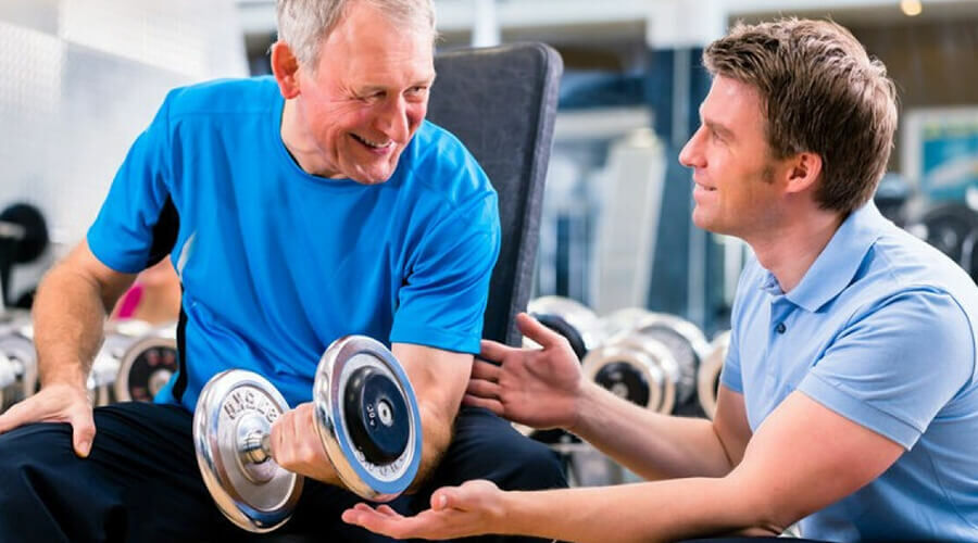 Egy idősebb férfi súlyzós edzést végez.