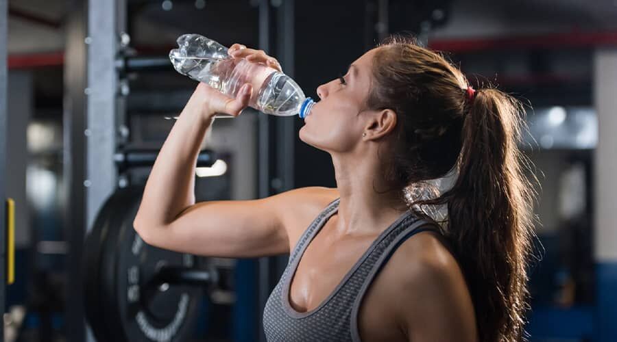 Megfelelő hidratáltság - egy nő palackozott vizet iszik
