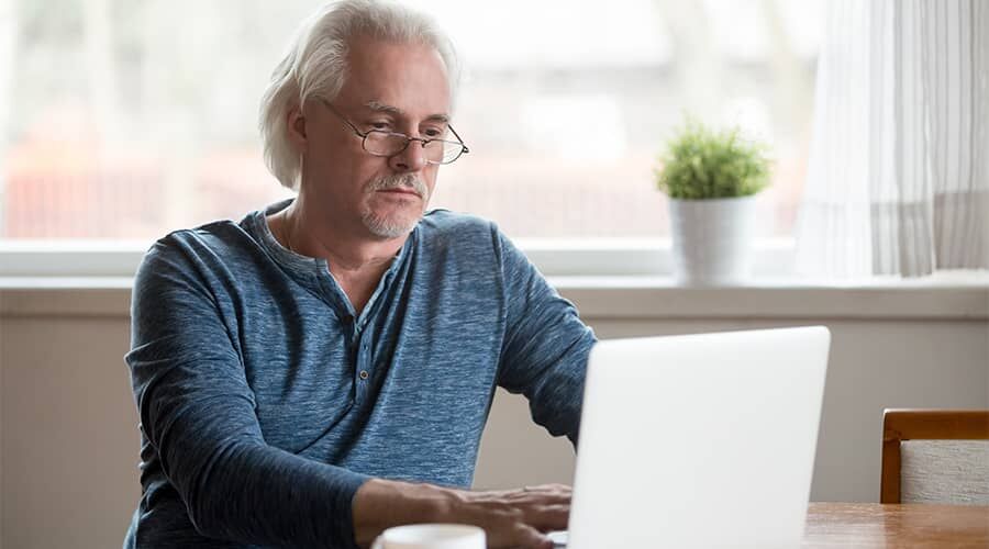 Idősebb gondterhelt férfi a laptop előtt
